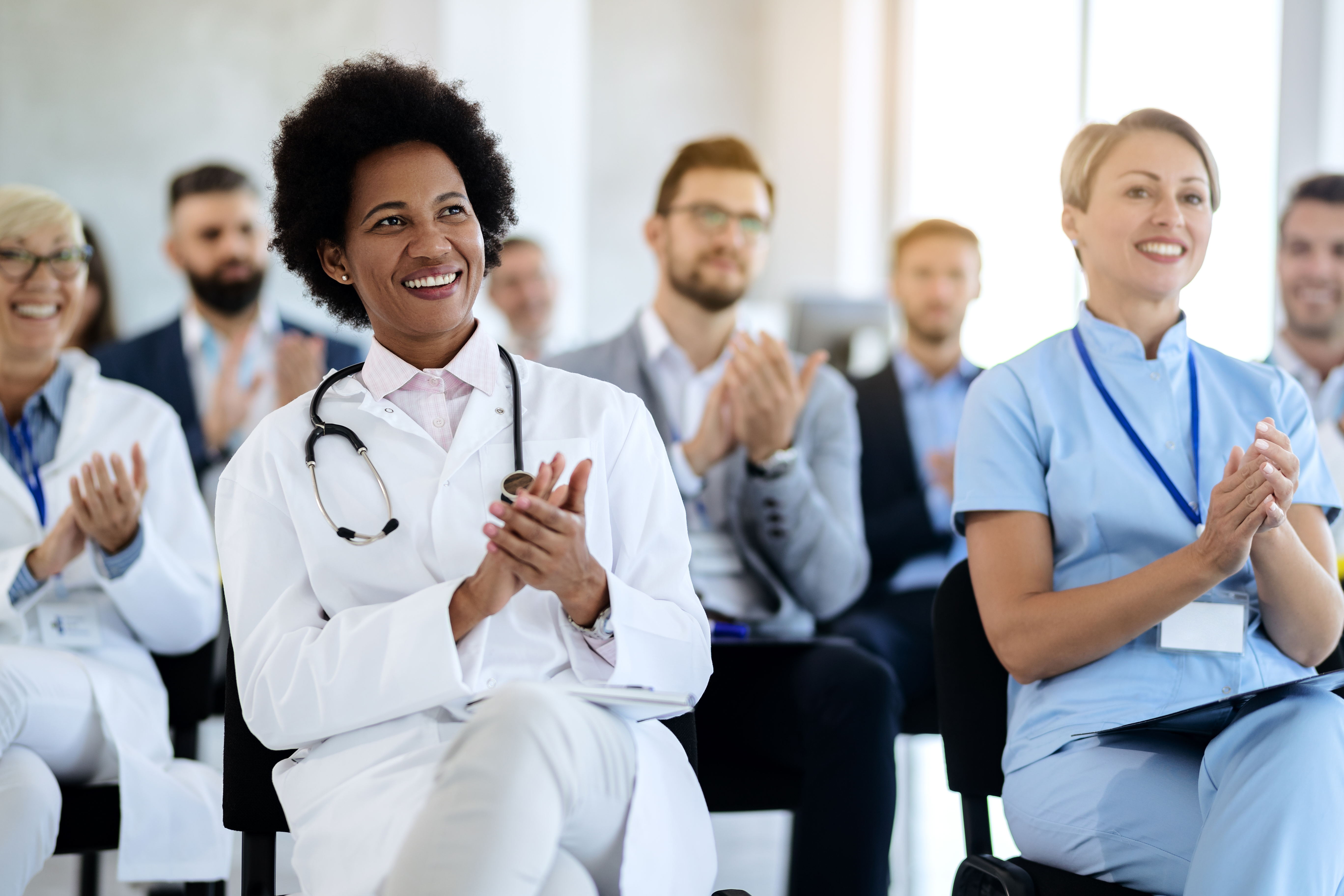 Doctors and medical professionals clap for a guest speaker