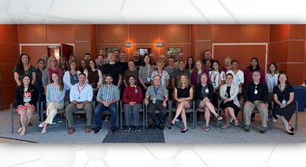 Group photo of approximately 50 DMCC members seated and standing in rows.